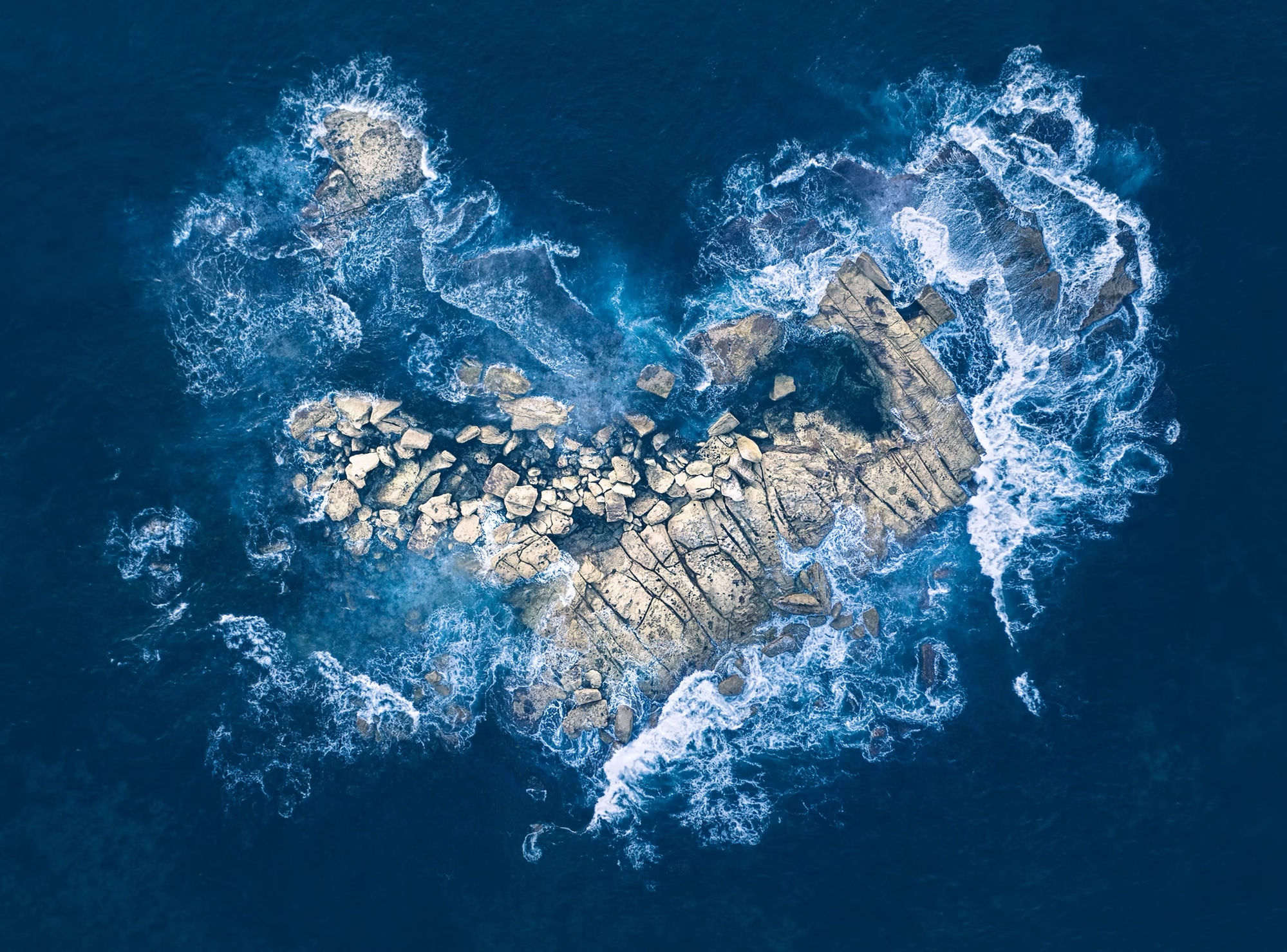 A heart-shaped stone resting on ocean rock