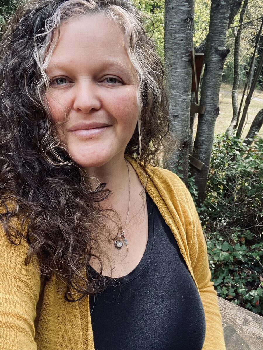 Heather, standing outdoors with trees and greenery in the background