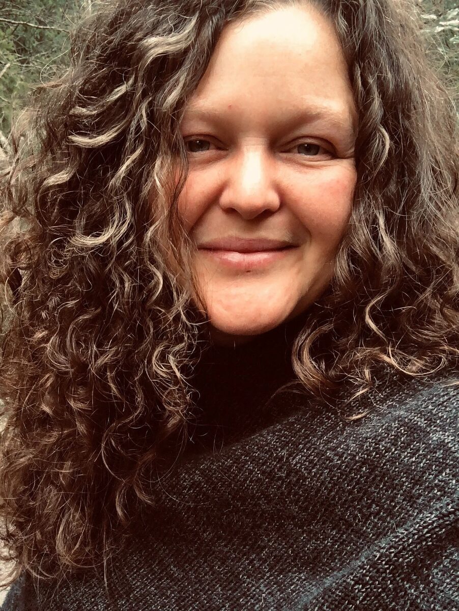Heather smiling outdoors, trees in the background