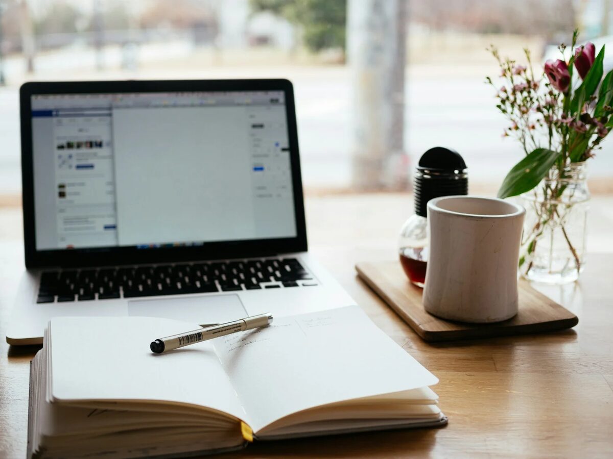A calm workspace with notebook, laptop and flowers